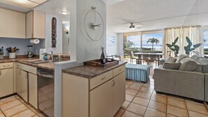 Eine moderne Küche mit Kochinsel, ein Essbereich mit Aussicht und ein Wohnzimmer mit Sofa.