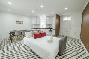 A hotel room with a bed, a dining table with chairs, a kitchen area, and a bathroom. - Lagarteiro House (Porto)