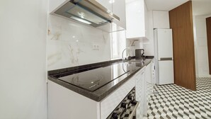 A modern kitchen with a black countertop, white cabinets, and a patterned floor. - Lagarteiro House (Porto)