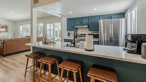 Una cocina moderna con una isla grande, electrodomésticos de acero inoxidable y taburetes de bar.