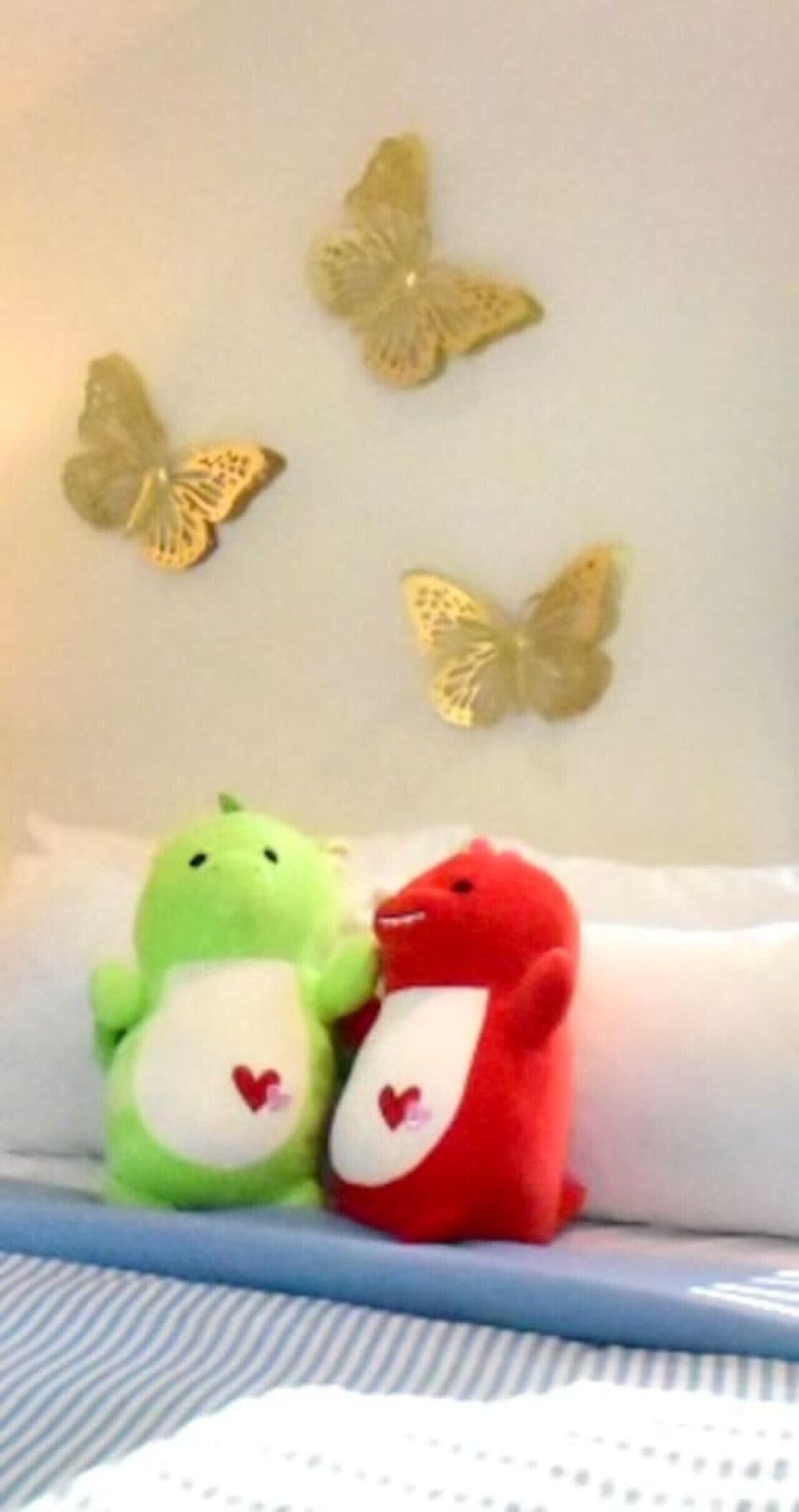 Una cama con peluches y mariposas decorativas en la pared.