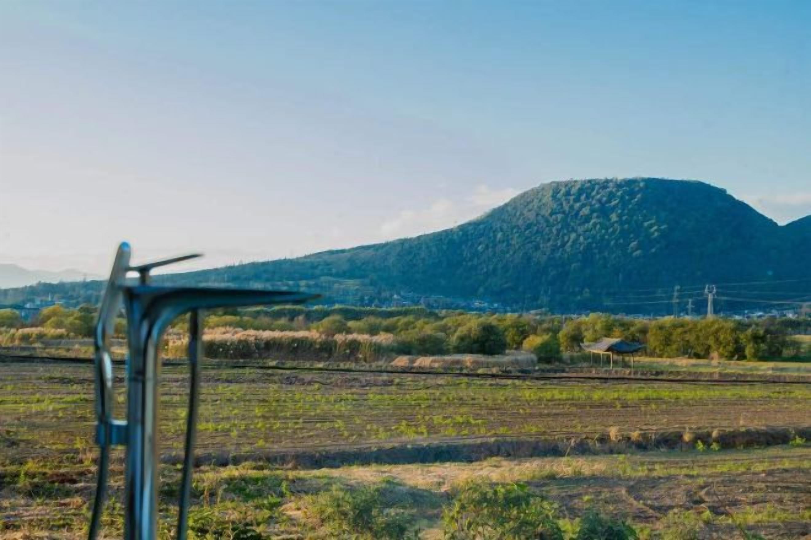 A rural landscape with a metal chair in the foreground and a mountain in the background.