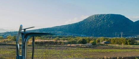 A rural landscape with a metal chair in the foreground and a mountain in the background.