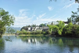 Vista fluvial de edificios tradicionales con una masa de agua tranquila al frente.