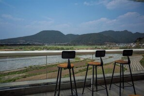 A terrace with three bar stools overlooking a river and mountains. - Tengchong Bailuyu Heshunqiu Shui Changtian·hot spring·wetland·inn (Tengchong)