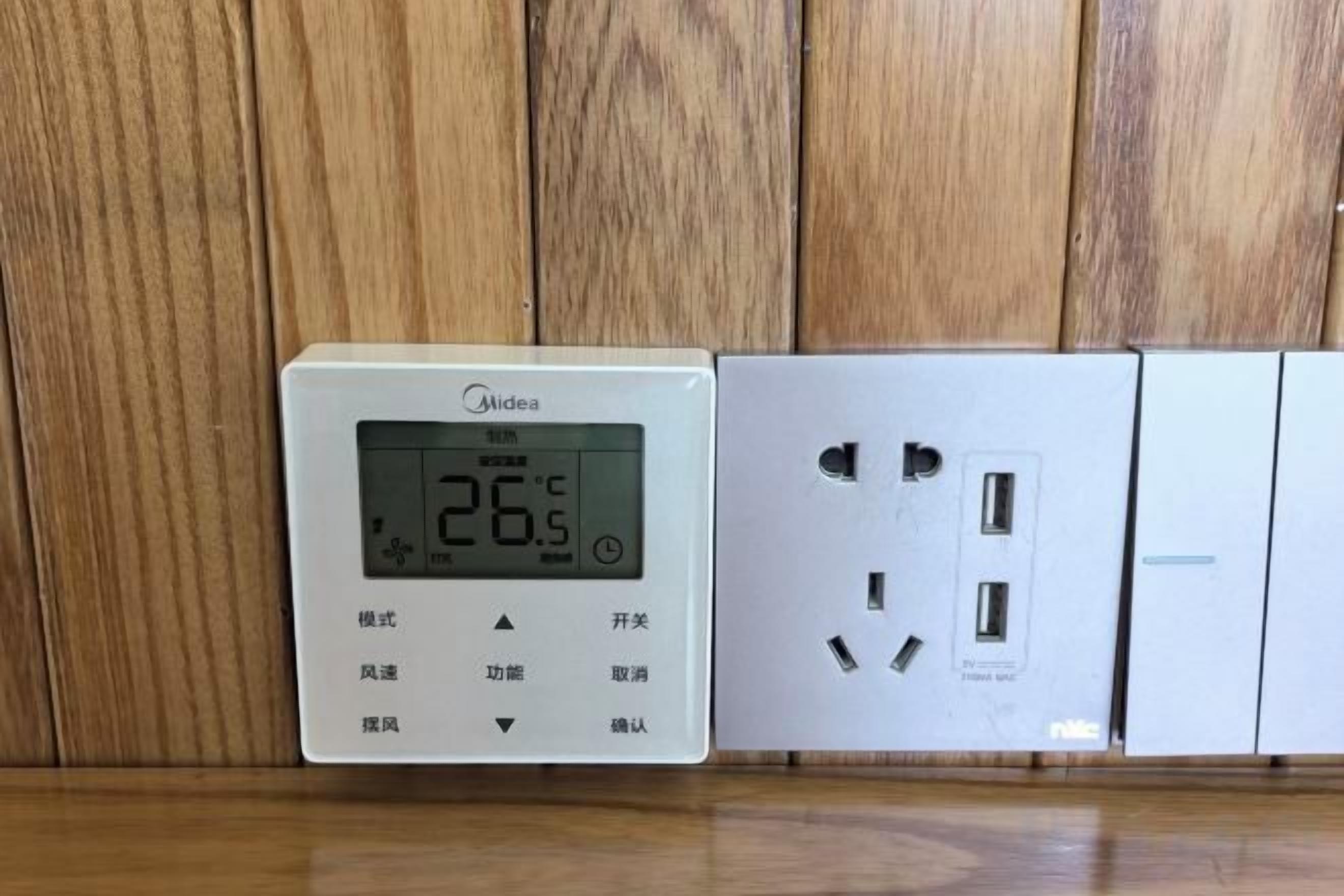 Termostato y toma de corriente sobre superficie de madera.