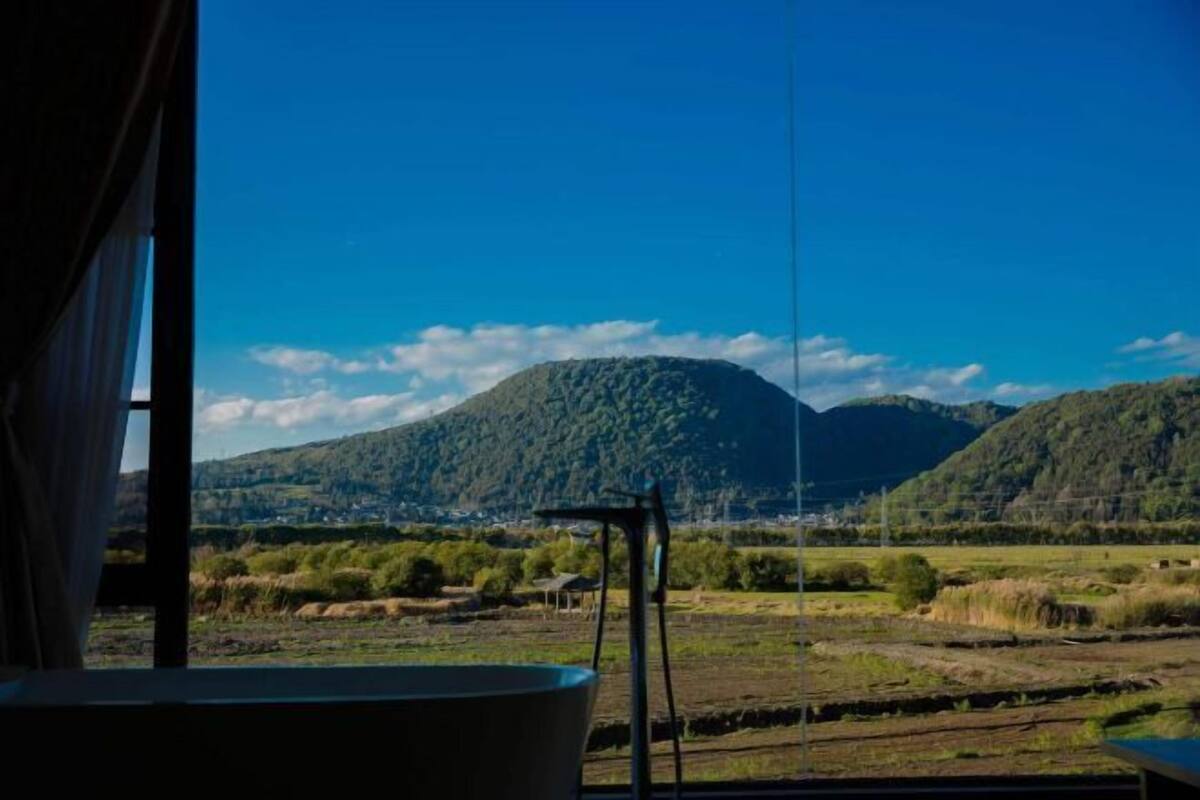 Quarto com uma grande janela que oferece vista para uma paisagem montanhosa.