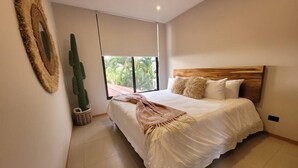 A bedroom with a large bed, a wooden headboard, and a view of greenery outside. - Casa Piña - Tamarindo 5 min Walk to Beach (Tamarindo)