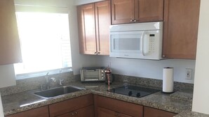 Eine Küche mit Granit Arbeitsplatten, Holzschränken, einer eingebauten Mikrowelle, einem Toaster und einem Spülbecken.