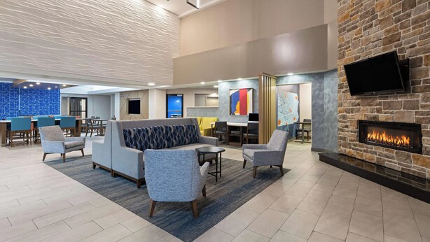 A lobby with a sofa, chairs, a fireplace, a TV, and a blue patterned wall. - Cozy 1-bedroom hotel with AC, fitness room in charming Harrisburg (Harrisburg)