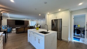 A modern kitchen with a central island, stainless steel appliances, and a built-in washer and dryer.