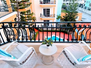 Un balcon avec deux chaises en osier blanc, une petite table ronde et une plante en pot.