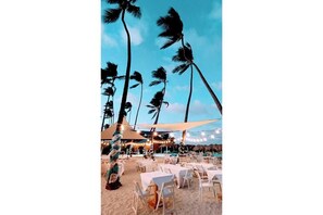 A beachside restaurant with outdoor seating, palm trees, and string lights. - Rooftop Penthouse Stargazing Walk 2 Beach & Fun (Punta Cana)