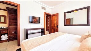 Ein Hotelzimmer mit Bett, Fernseher, Kleiderschrank und Spiegel.