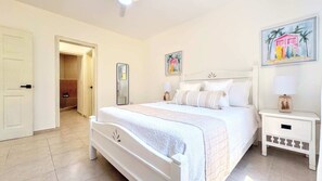 A bedroom with a bed, a bedside table, a mirror, and a door leading to a bathroom.