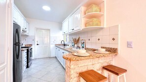 A kitchen with white cabinets, a granite countertop, a built-in oven, and a stainless steel refrigerator.