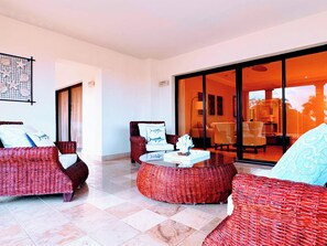 A spacious outdoor seating area with wicker furniture and a glass door leading to an interior space.