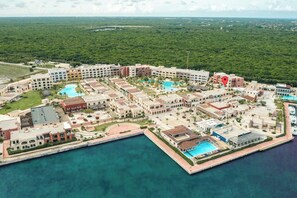 An aerial view of a resort with multiple buildings, a central pool, and a marina. - Your Private Pool, Marina Resort & Grounds (Punta Cana)