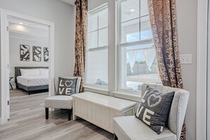 A modern bedroom with a bed, a bench, and a window with curtains. - Laurie Luxe:  3/2 Home w/ Hot Tub, Massage Chair & Games. 1.5 miles from beaches (Panama City Beach)