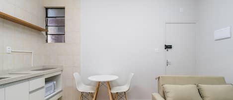 Un espacio habitable compacto con kitchenette, un área de comedor con dos sillas y un sofá.