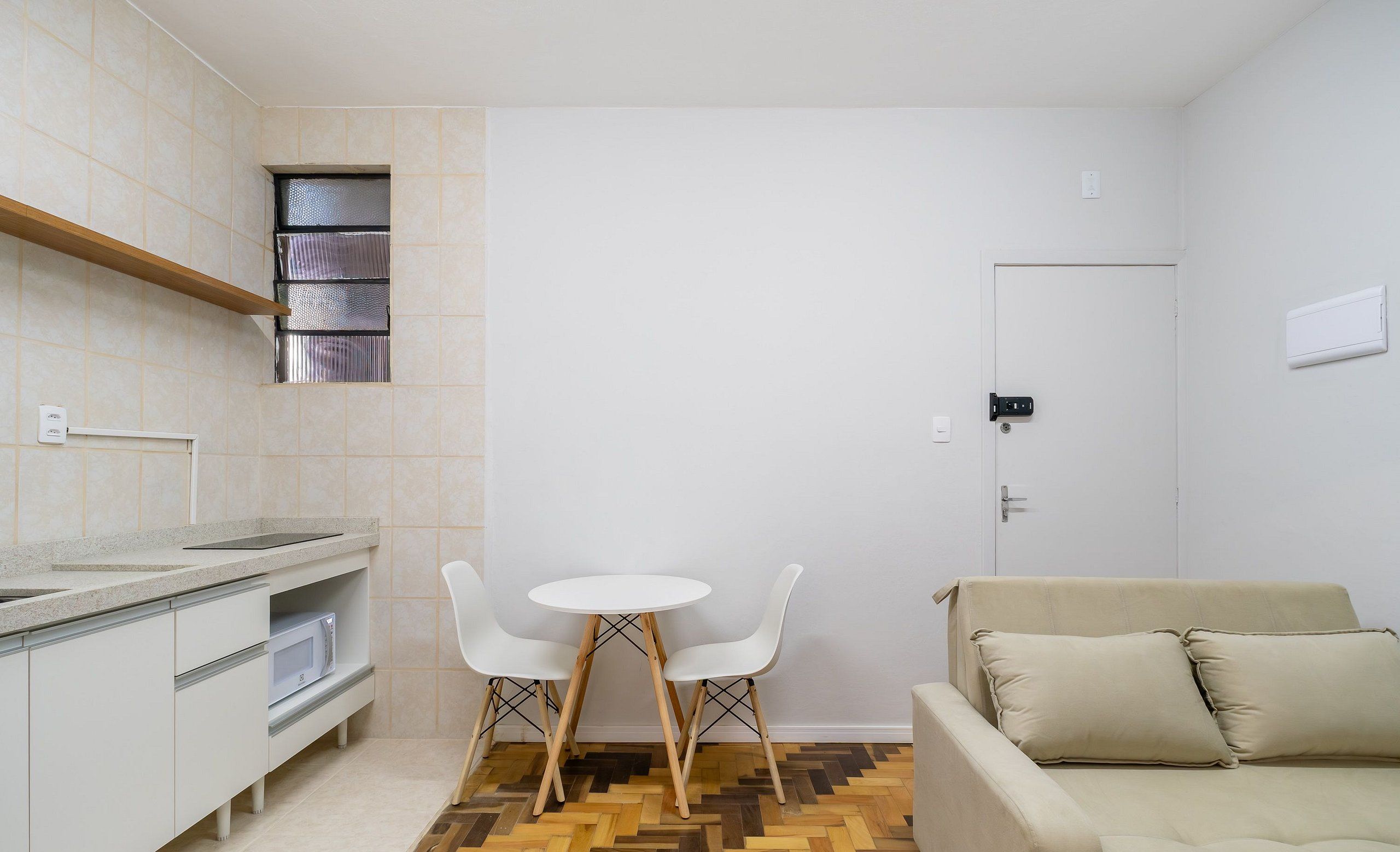A compact living space with a kitchenette, a dining area with two chairs, and a sofa.