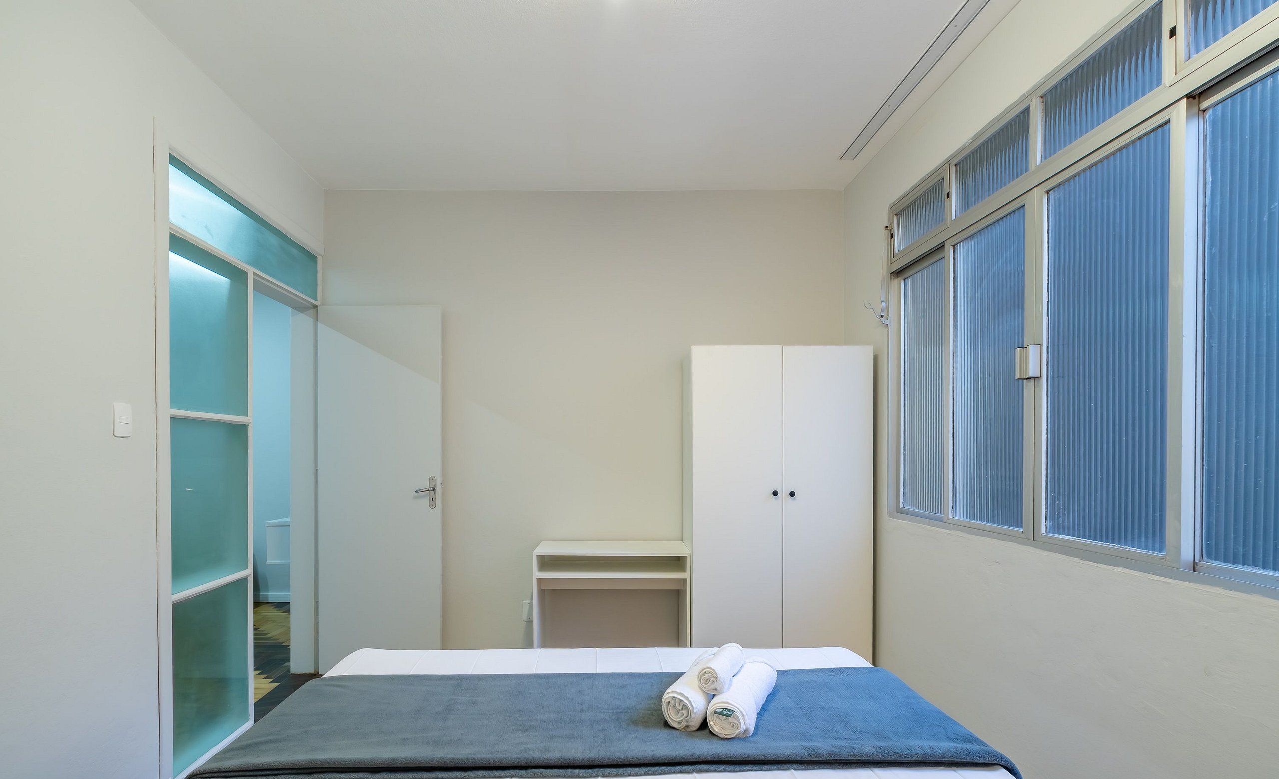 A bedroom with a bed, a wardrobe, and a window.