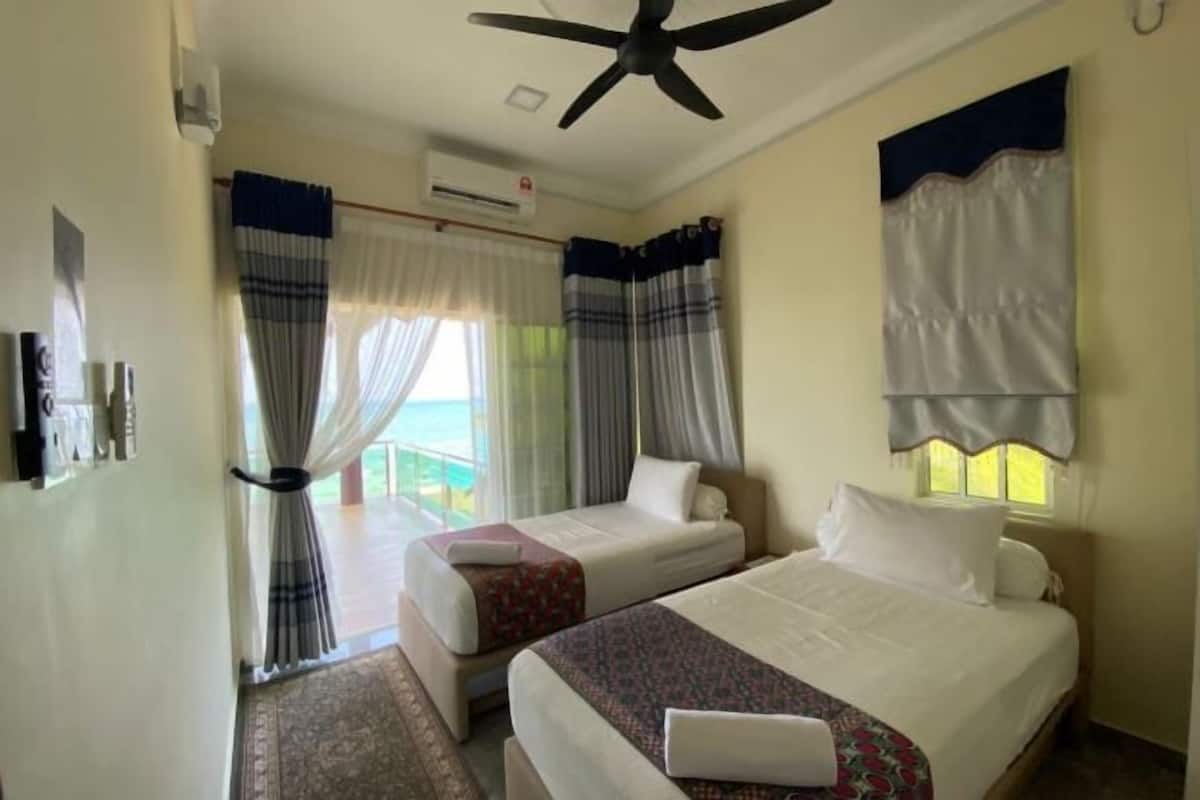 A hotel room with two beds, a ceiling fan, an air conditioning unit, and a view of the outdoors.
