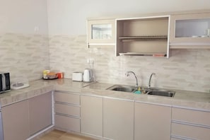 A kitchen with a sink, countertop, cabinets, and a microwave. - Che Beach House (Rusila)