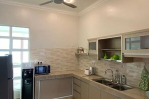 Una cocina con refrigerador, microondas y pileta.