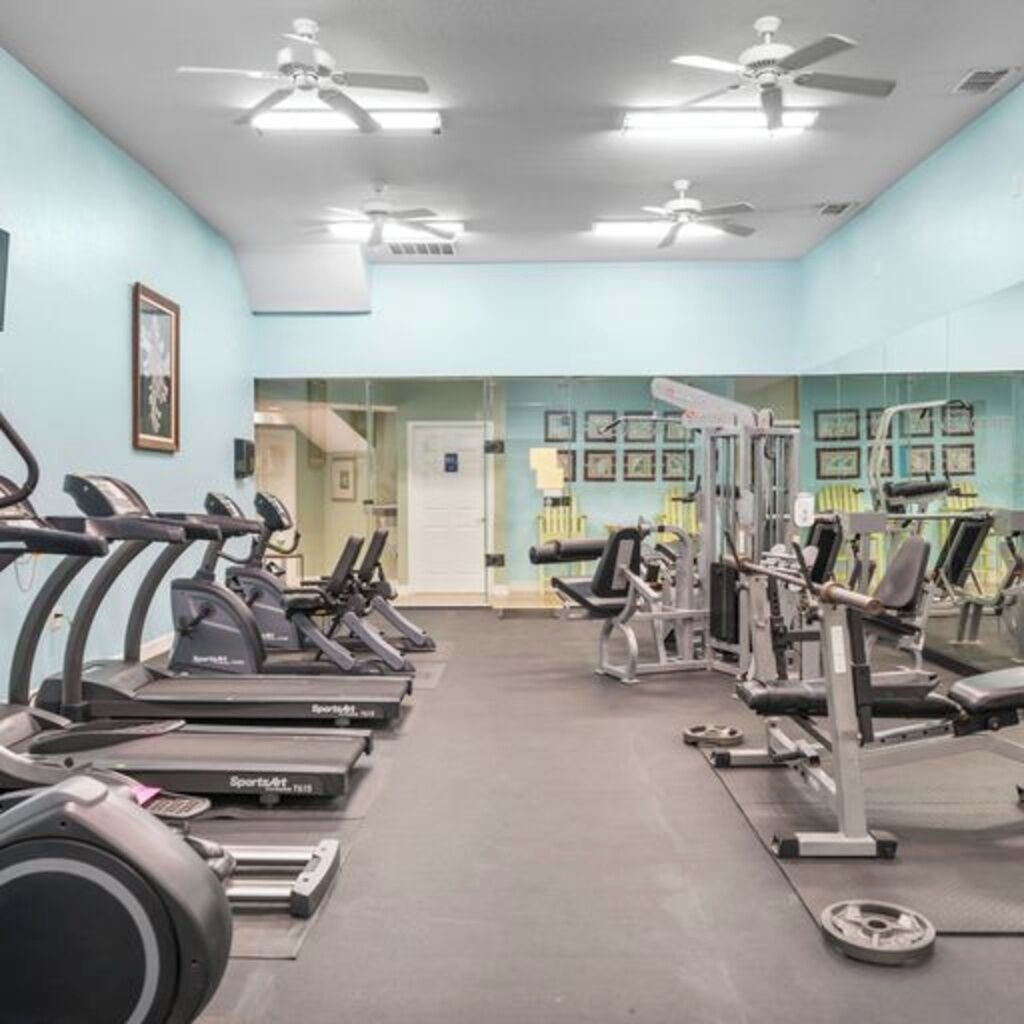 Una palestra con tapis roulant, macchinari per pesi e ventilatori a soffitto.