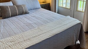 Un letto con copriletto trapuntato, una testiera in legno e due cuscini.