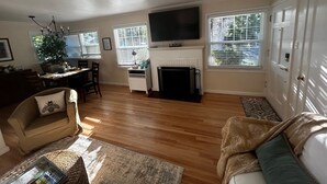 A living room with a fireplace, a television, and a dining area with a Christmas tree.