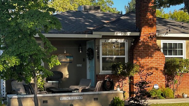 A house with a porch, a brick chimney, and a sign welcoming visitors.