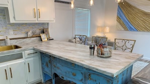 A kitchen with a marble countertop, white cabinets, and a blue cabinet with decorative elements. - 3rd of 3 Luxury Tiny Homes at PALMER LEGACY- “Gladys Faye“  Unit 3- blue (Tuscaloosa)