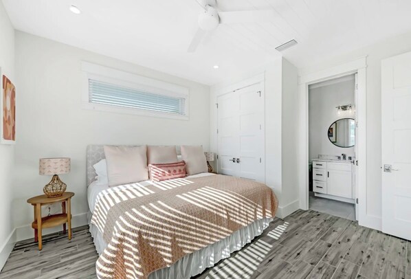 Un dormitorio con cama, mesita de noche, ventana con persianas, armario y baño con espejo.