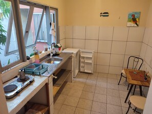 Een koelkast, een kookplaat, kookgerei, borden en bestek