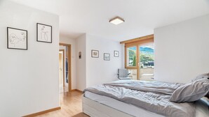 Una camera da letto con un letto grande, pavimento in legno e vista su un balcone.