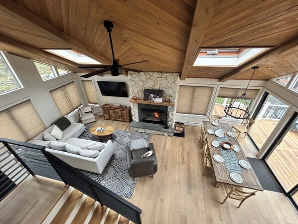 Ein geräumiges Wohnzimmer mit Kamin, Essbereich und einer Treppe, die in einen oberen Bereich führt.