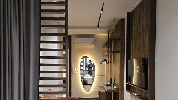 Una habitación de hotel moderna con cama, televisor, espejo y baño con tocador.