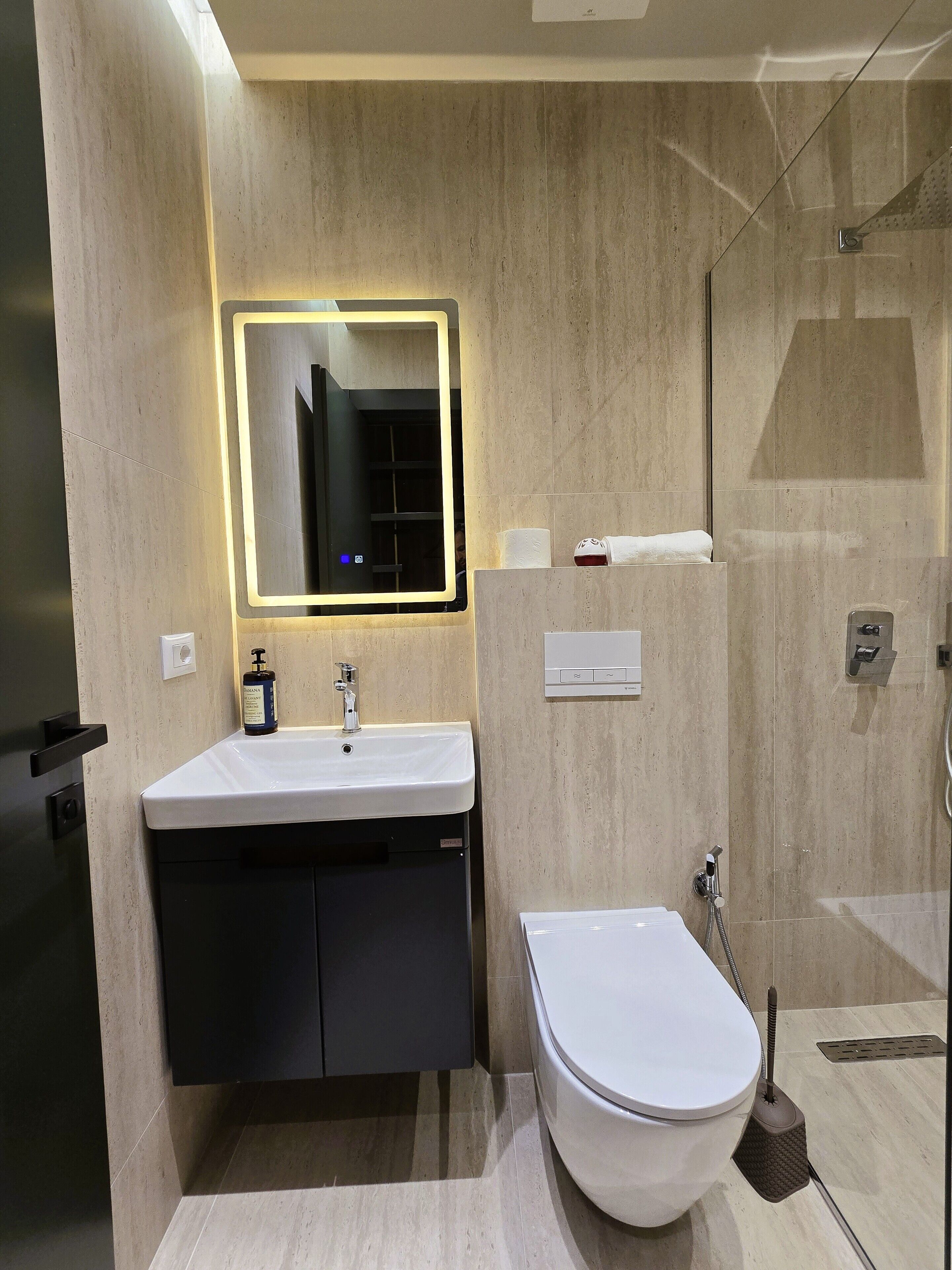 A modern bathroom with a sink, mirror, toilet, and shower.