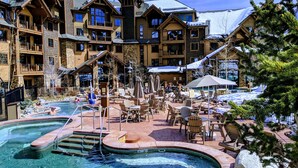 Un resort con varias piscinas, mobiliario exterior y un paisaje cubierto de nieve.