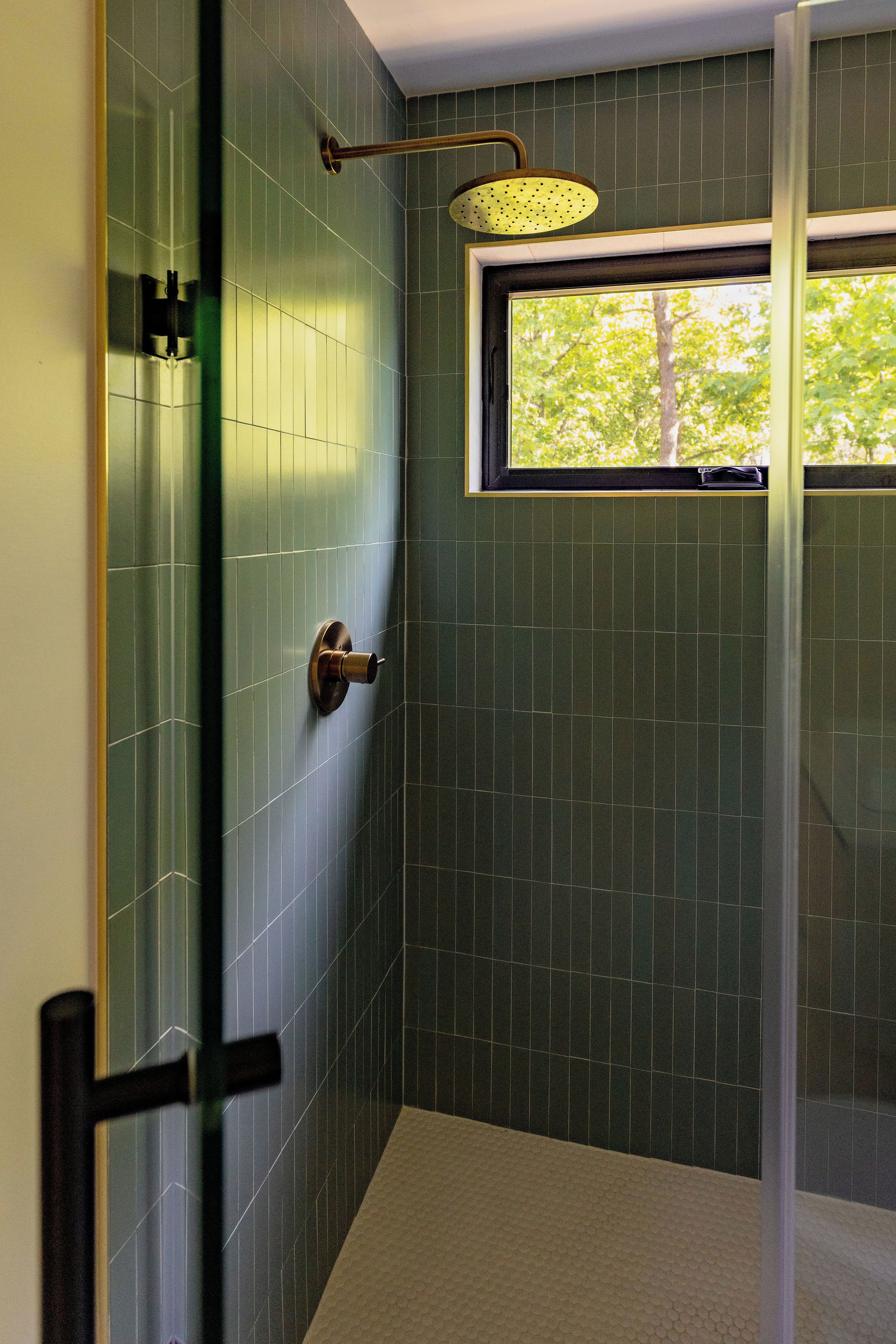 A shower with a glass door, a window, and a towel rack.