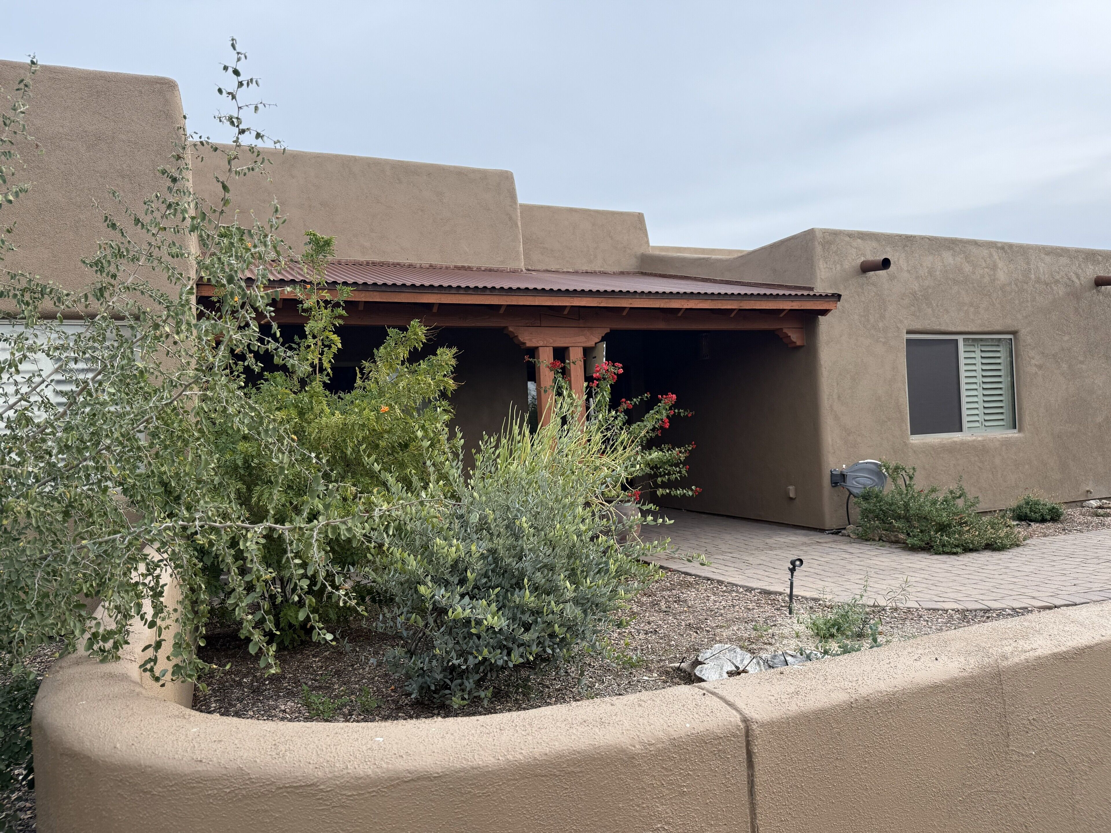 A building with a flat roof, a covered entrance, and a window with shutters.