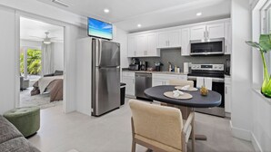 A modern kitchen with white cabinets, stainless steel appliances, and a flat-screen TV. - Cozy 1BR w/ Pool · 4 min from Siesta (Sarasota)