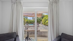 A room with a view of an outdoor pool area, featuring a patio with chairs and a table. - Cozy 1BR w/ Pool · 4 min from Siesta (Sarasota)