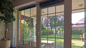 A room with a large sliding glass door leading to a patio with a table and chairs, a potted plant, and a radiator.