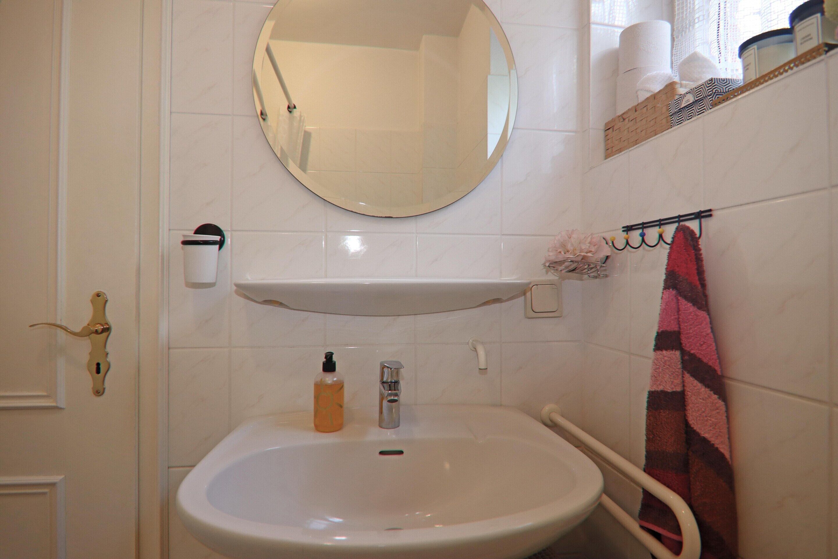 A bathroom with a sink, mirror, towel rack, and toiletries.
