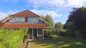 A two-story house with a red-tiled roof, large windows, and a well-maintained garden.