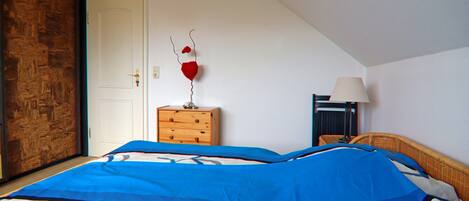 A bedroom with a bed, a dresser, a lamp, and a door.