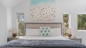 A bedroom with a large bed, two bedside lamps, a window with blinds, and a wall art piece. - Island Sol:  Secluded 4 BR Paradise with Salt Water Pool, Walk to the Village (Siesta Key)